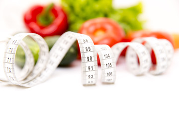 Fitness and healthy food diet concept. Fresh green vegetables, measuring tape isolated on white...
