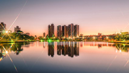 Sunset at a lake of a park with the city on background - obrazy, fototapety, plakaty