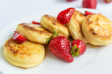 Delicious curd fritters with strawberry on a white plate