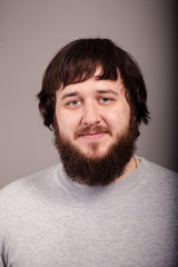 Obraz premium close-up young bearded and mustache guy looks straight in front of gray background