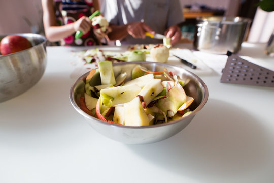 Bowl of apple  peelings  with two people in background