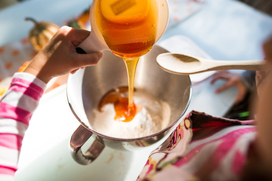Pouring honey into mixing bowl