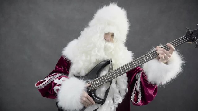 Santa claus plays of the christmas melody jingle bells on the bass guitar