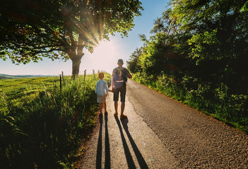 Father and son walk on sunset road