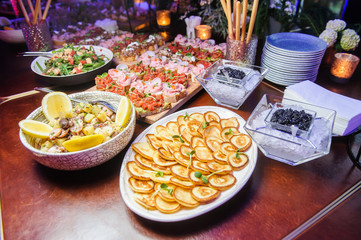 Black caviar and pancakes.Selective focus/Black caviar, pancakes, salads and other snacks on serving table