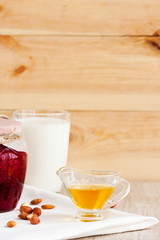 Honey, raspberry jam, milk, towel on rustic background. Candied fruits on a towel. Healthy food. Breakfast. White napkin on the table. The background. Frame
