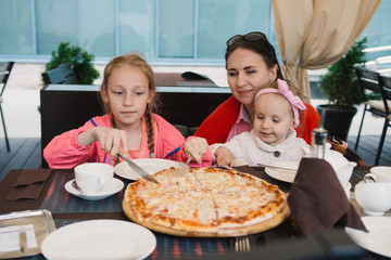 Mom and children eating pizza at a cafe