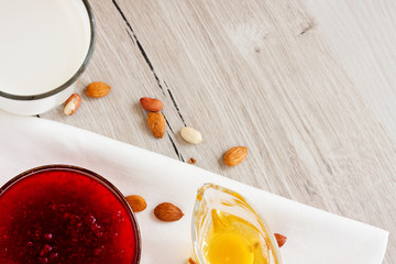 Honey, raspberry jam, milk, towel on rustic background. Candied fruits on a towel. Healthy food. Breakfast. White napkin on the table. The background. Frame
