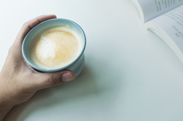 Blue coffee cup on the desk with books. Concept coffee lover background.