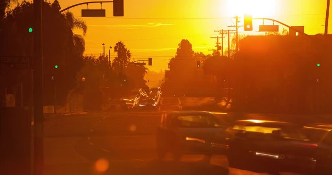 Time Lapse of the sun rising behind a busy street filled with traffic.
