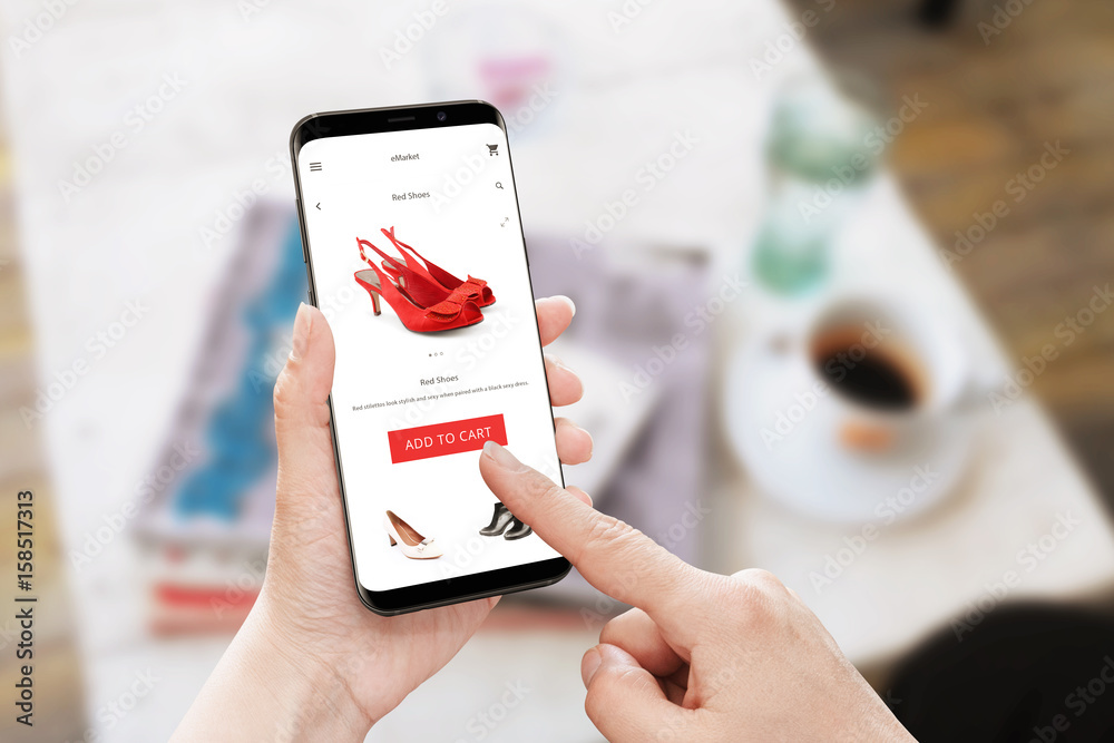 Poster add to cart red shoes on online store. modern smart phone with round edges in woman hand. table with