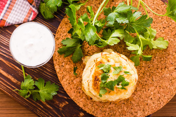 Оладьи из кабачков, соус и петрушка на деревянном фоне