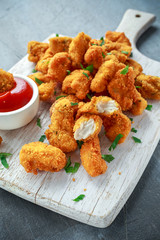 Fried crispy chicken nuggets with ketchup on white board