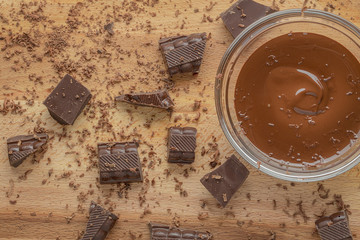 Melted and chocholate pieces on wood table