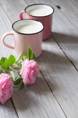 Two pink cups with milk on a white wooden table