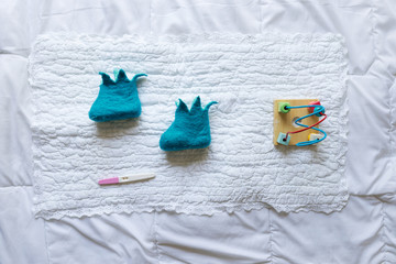 Baby shoes with toys and pregnancy  test on white background