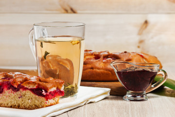 Pie with cherries, cherry jam, tea and white napkin on the table. Dessert, sweet, tea. Green tea. Early morning, breakfast. The background
