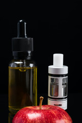 Electronic cigarette and liquid with a taste of a red apple on a black background