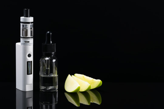 Electronic cigarette and liquid with the taste of a green apple, on a black background