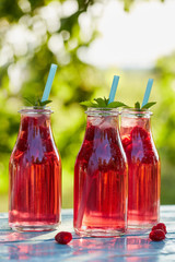 Fototapeta na wymiar Three glasses of lemonade with raspberries and mint leaves