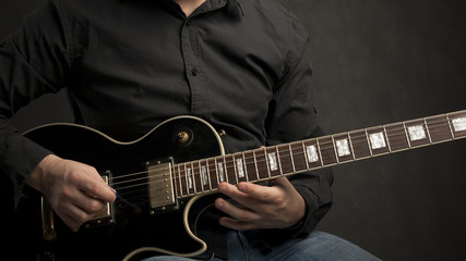 Obraz na płótnie Canvas Man in shirt playing black electric guitar