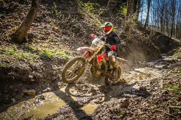 Fototapeten Motocross rider passes through the mud on the hardenduro race © Glasco