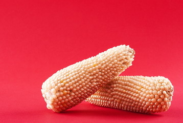Raw corn on a red background © Valerii Dekhtiarenko
