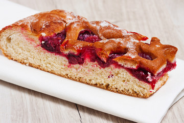 A cake with a cherry on a white napkin on a table. Dessert, sweet, tea. Tea. Early morning, breakfast. The background. Cherry on the cake
