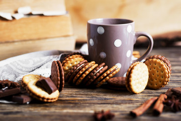 Sweets and desserts, chocolate and milk biscuits sandwich, cracker with cinnamon and tea on a dark wooden rustic background 