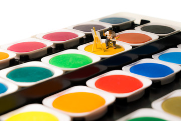Kleiner Künstler malt inmitten eines riesigen Deckfarbenkastens