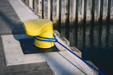 Yellow mooring bollard on pier with mooring rope