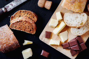 Alcoholic drinks, a holiday, white sparkling wine, glasses with champagne with freshly baked bread, mozzarella cheese and dark chocolate on a black wooden background 