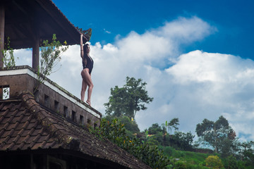 Girl in swimsuit stay on the roof in the mystical abandoned rotten hotel in Bali with blue sky. Indonesia