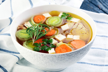 Broth with carrots, onions various fresh vegetables in a pot - colorful fresh clear spring soup....
