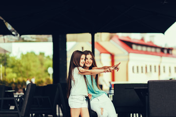 Mother and daughter sitting in street cafe summer time