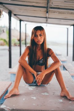 Beautiful girl sitting on the concrete table beneath the sunshade