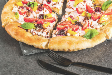 Summer snacks. Food for party. Fruit pizza with cream, currants, yogurt, strawberries, mango, peaches, bananas, blackberries, chocolate, walnuts, mint. On black table. Copy space