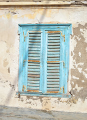 Fototapeta na wymiar old blue wooden window with rust - abandoned house Hydra island Greece