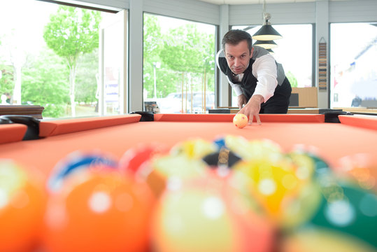 Man poised to hit cue ball on pool table