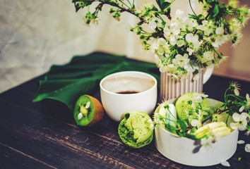 Green macarons on a wood table for coffee or a tea with the blossom flowers on background