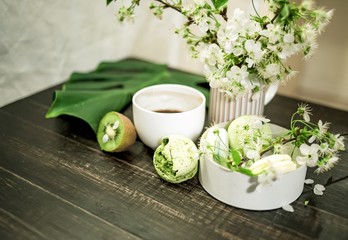 Green macarons on a wood table for coffee or a tea with the blossom flowers on background