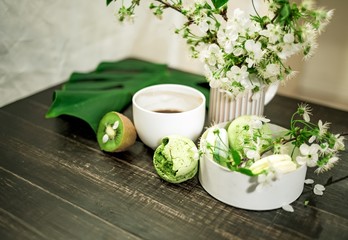 Green macarons on a wood table for coffee or a tea with the blossom flowers on background