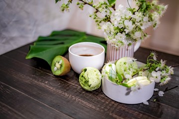 Green macarons on a wood table for coffee or a tea with the blossom flowers on background