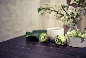Green macarons on a wood table for coffee or a tea with the blossom flowers on background