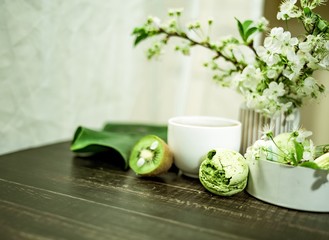 Green macarons on a wood table for coffee or a tea with the blossom flowers on background