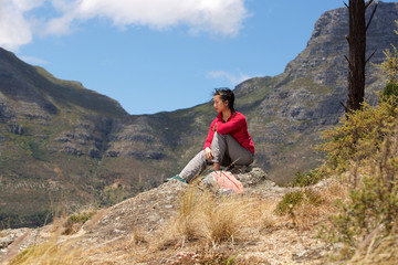 asian female hiker sitting on peak and looking at view
