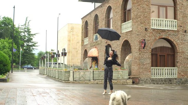 young woman fooling around in the rain with the dog