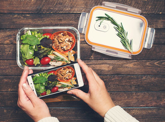  Female hands taking photo of salad and chiken lunch box with smart phone. Close up of woman hands taking picture of food. © Polina Ponomareva