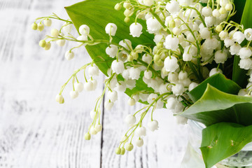 Fresh spring flowers bouquet with lily of the valley on a wooden table