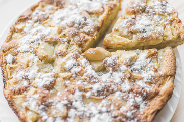 Apple pie and a cut piece of pie with powdered sugar